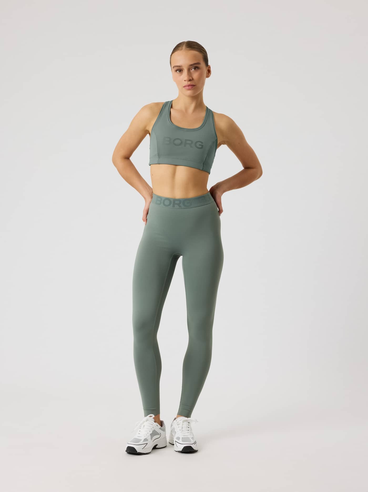 Full-body front view of a woman in slim-fit Borg Tights in Agave Green (Green) for training with a tonal branded waistband. - Image 4