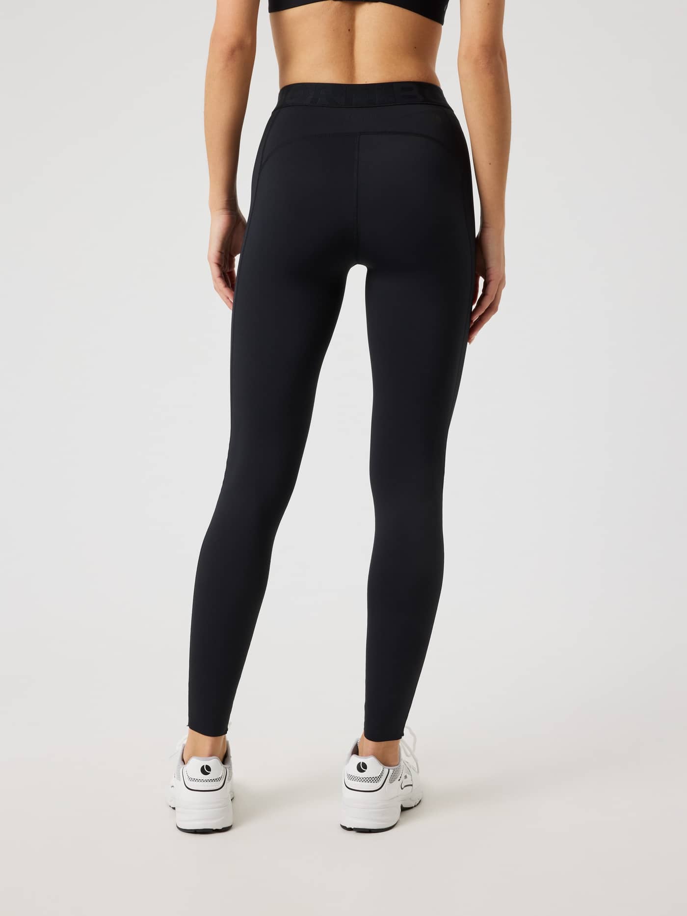 Back view of a woman wearing the slim fit Borg Tights in Black Beauty (Black) with a black logo for training performance. - Image 2
