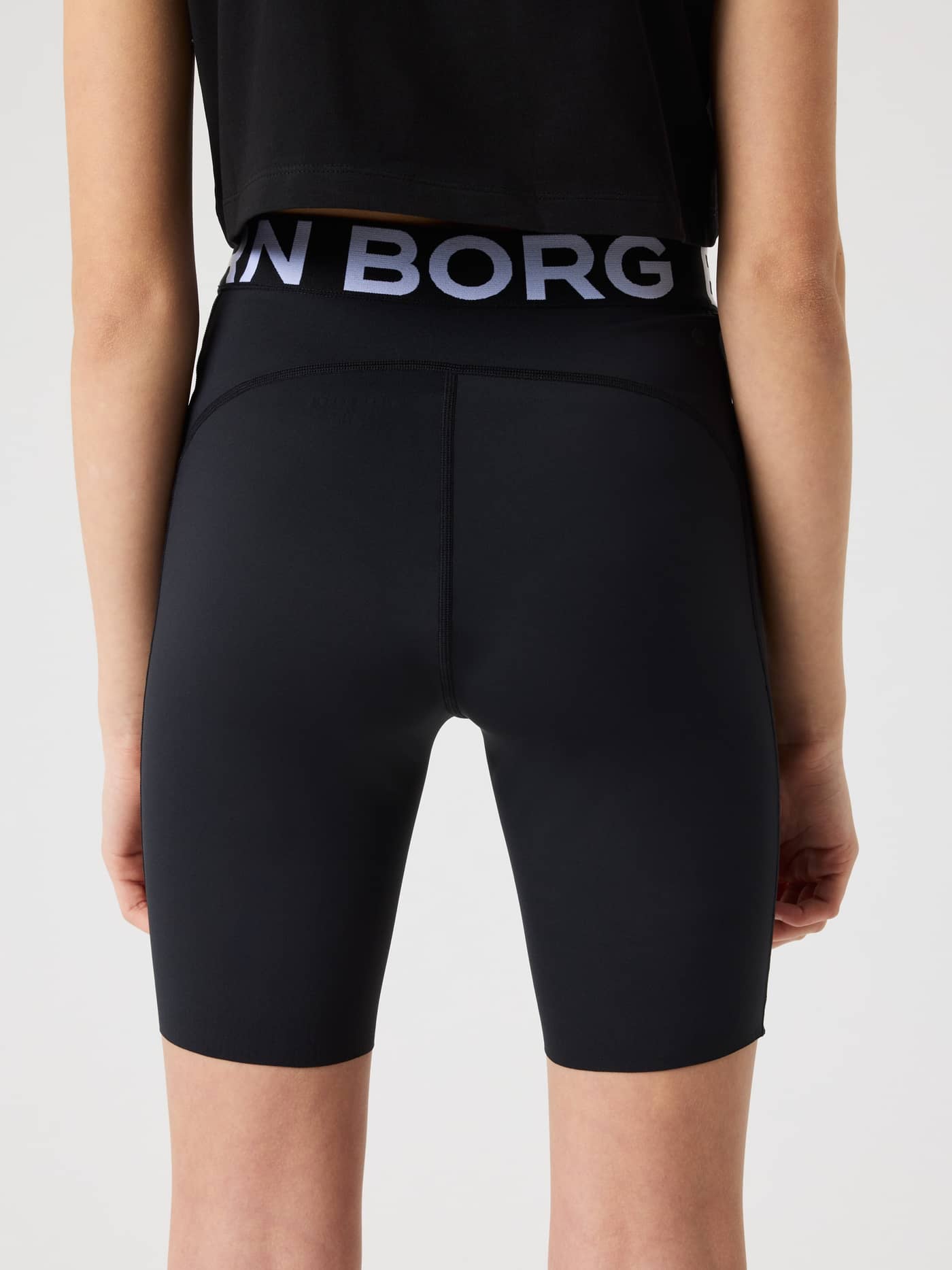 Back view of a model wearing kids training and running Borg Short Tights in Black Beauty (Black) with a branded waistband. - Image 2