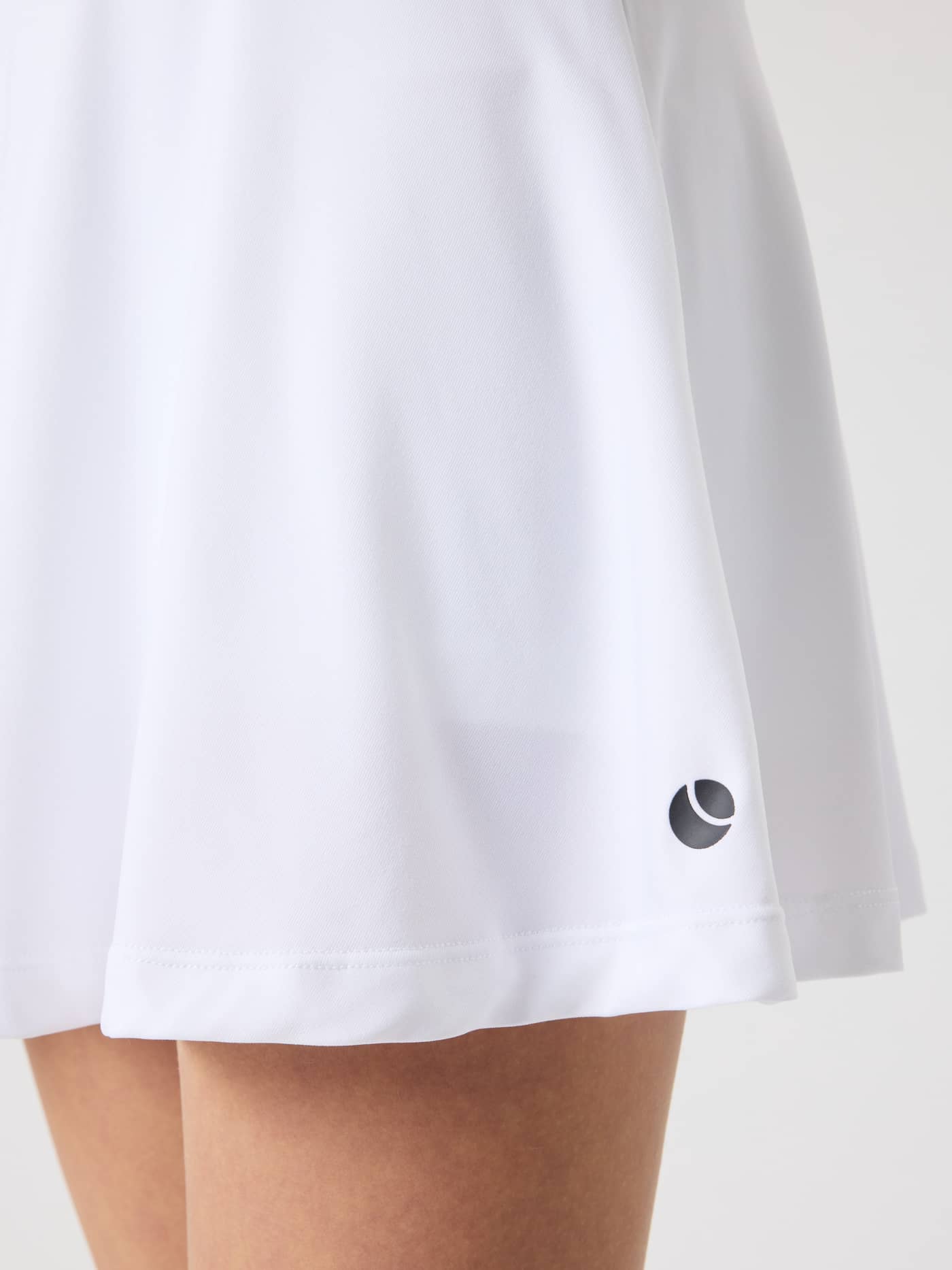 Nærbilde av Ace Jersey Skirt til kids i Brilliant White (Hvit) i myk ribbjersey med en svart tennislogo. - Image 6