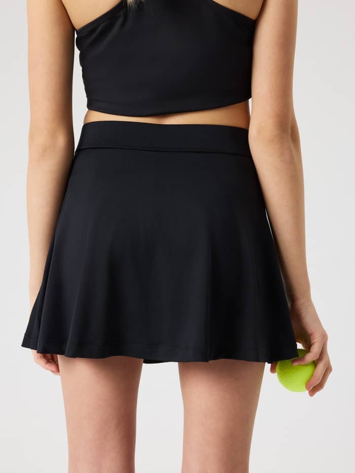 Back view of kids wearing the Ace Jersey Skirt in Black Beauty (Black), offering a stylish fit for tennis performance. - Image 2
