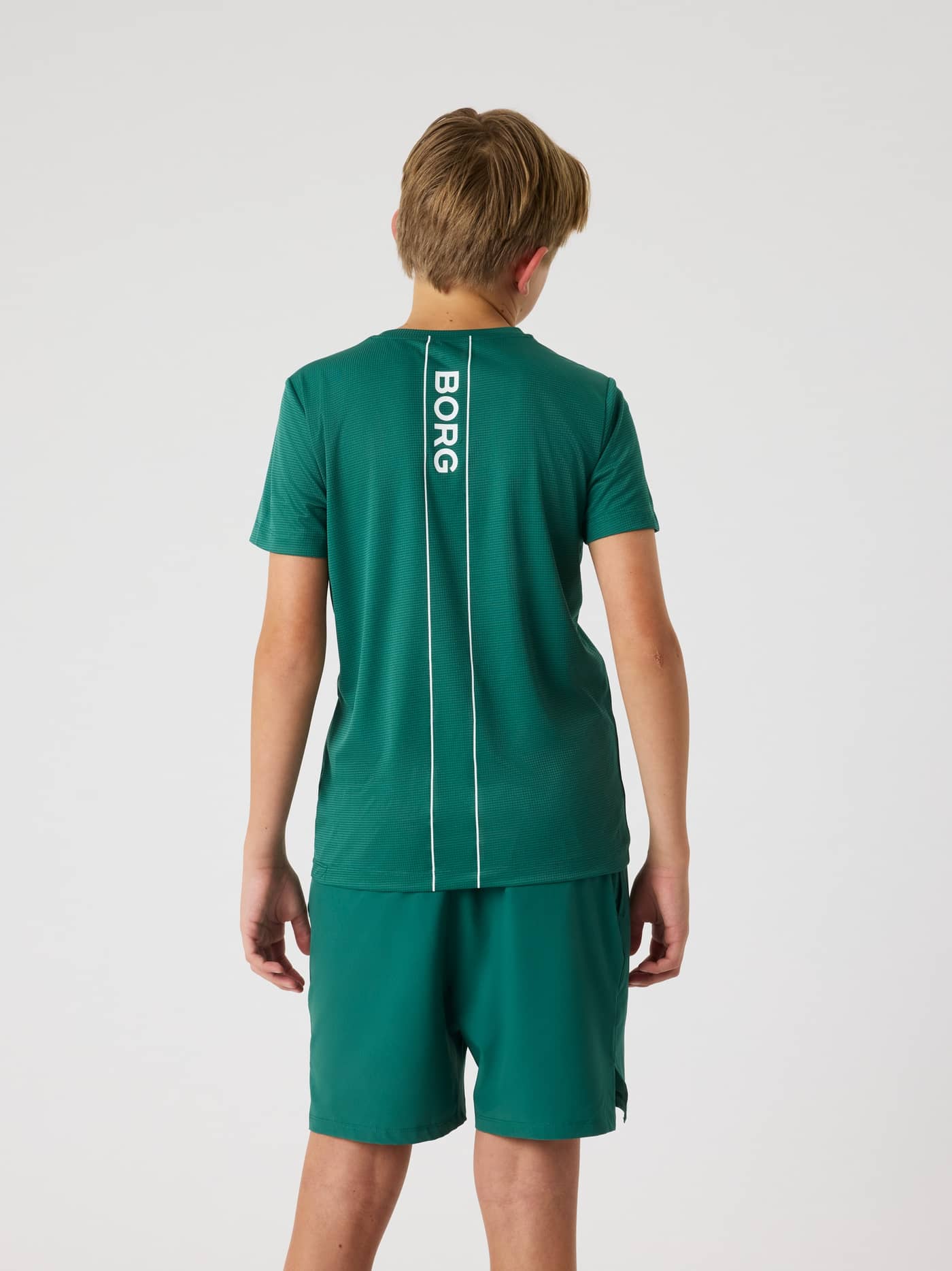 Bakifrån på en modell i kids Ace Light T-Shirt i Posy Green (Grön) med en vit randig Borg-logotyp för tennis och träning. - Image 4