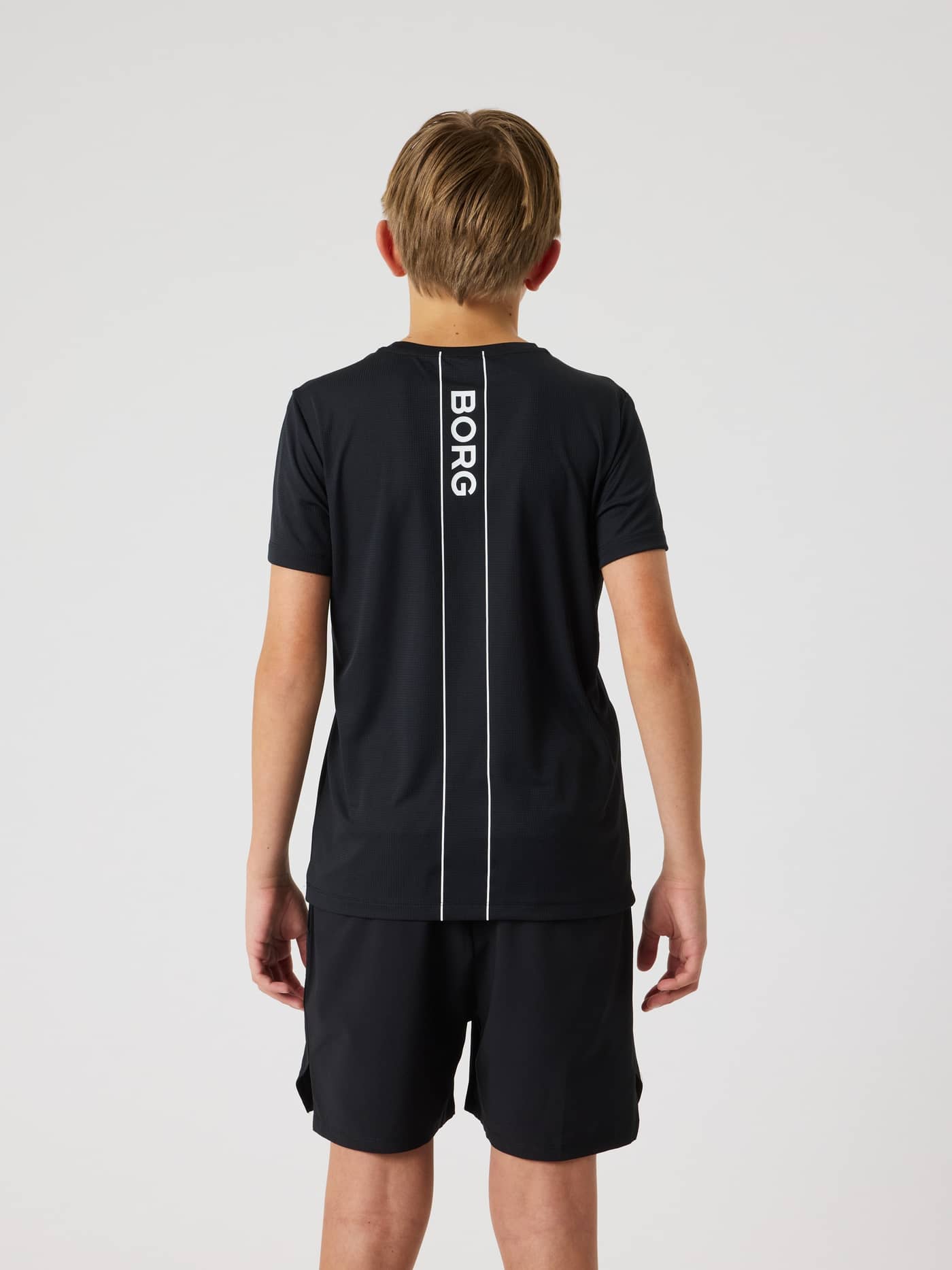Achteraanzicht van kids in het Ace Light T-Shirt in Black Beauty (Zwart) met wit verticaal Borg-logo voor tennis. - Image 2