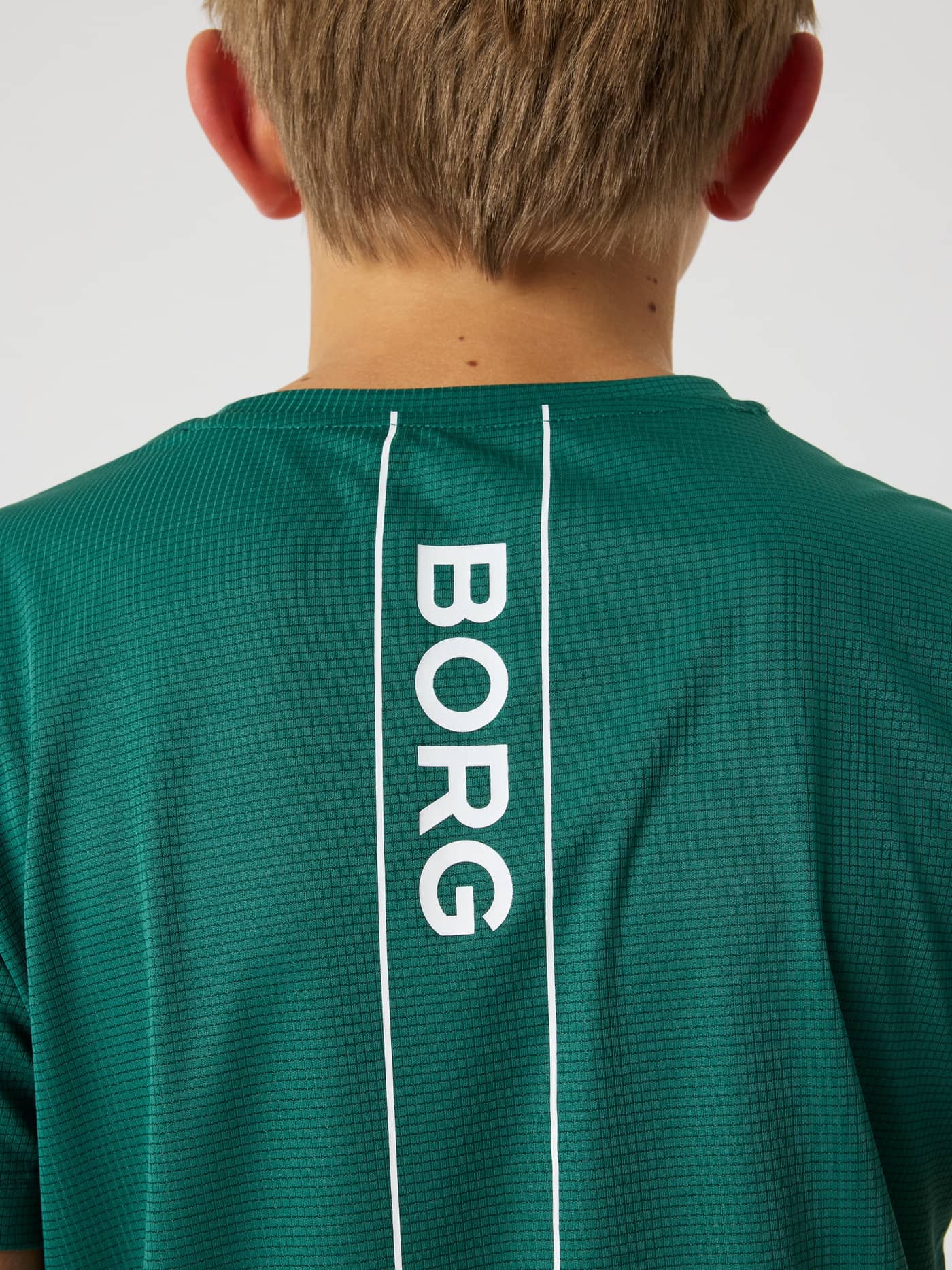Närbild bakifrån på Björn Borg Ace Light T-Shirt för kids i Posy Green (Grön) för tennis med vit BORG-logga i en rand. - Image 3
