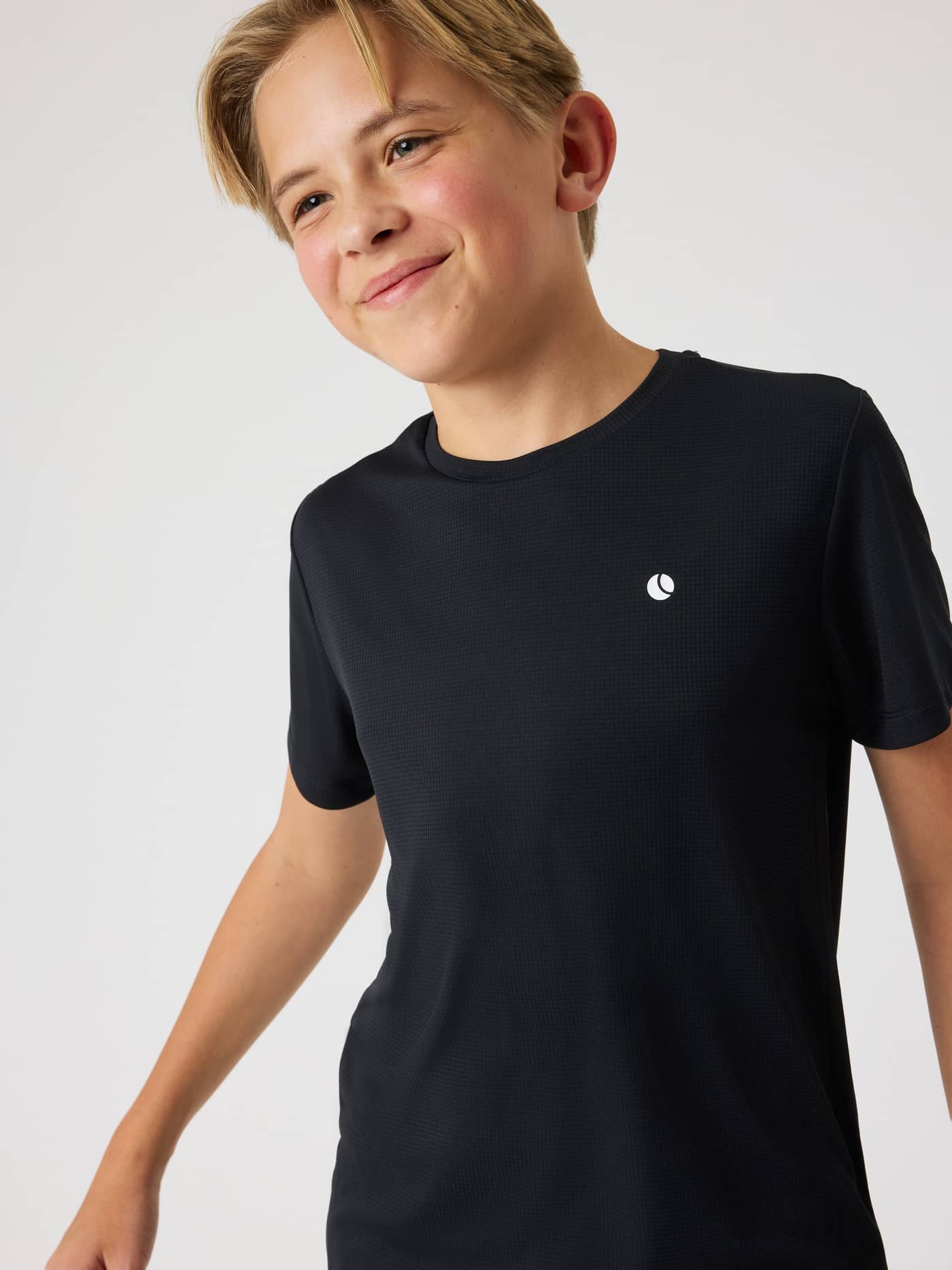 Vooraanzicht van een kind in het Björn Borg Ace Light T-Shirt in Black Beauty (Zwart) met wit ACE-ballogo voor tennis. - Image 6