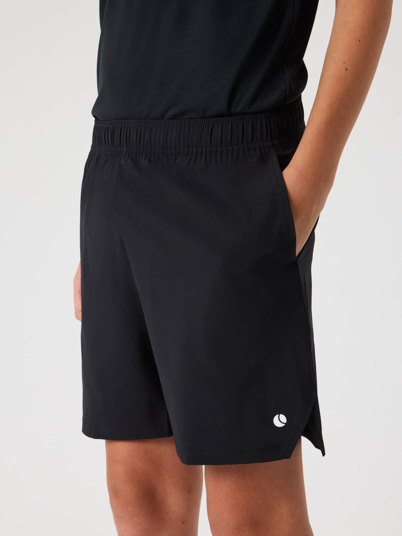 Side-front view of a kid wearing the Ace Racquet Shorts in Black Beauty (Black) for performance tennis play. - Image 1