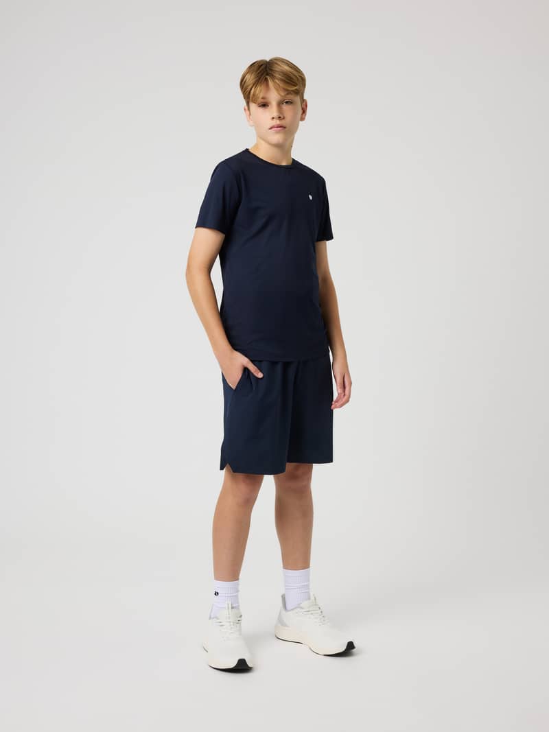 Full-body front view of a kid wearing Ace Racquet Shorts in Night Sky (Navy), designed for tennis and performance.
