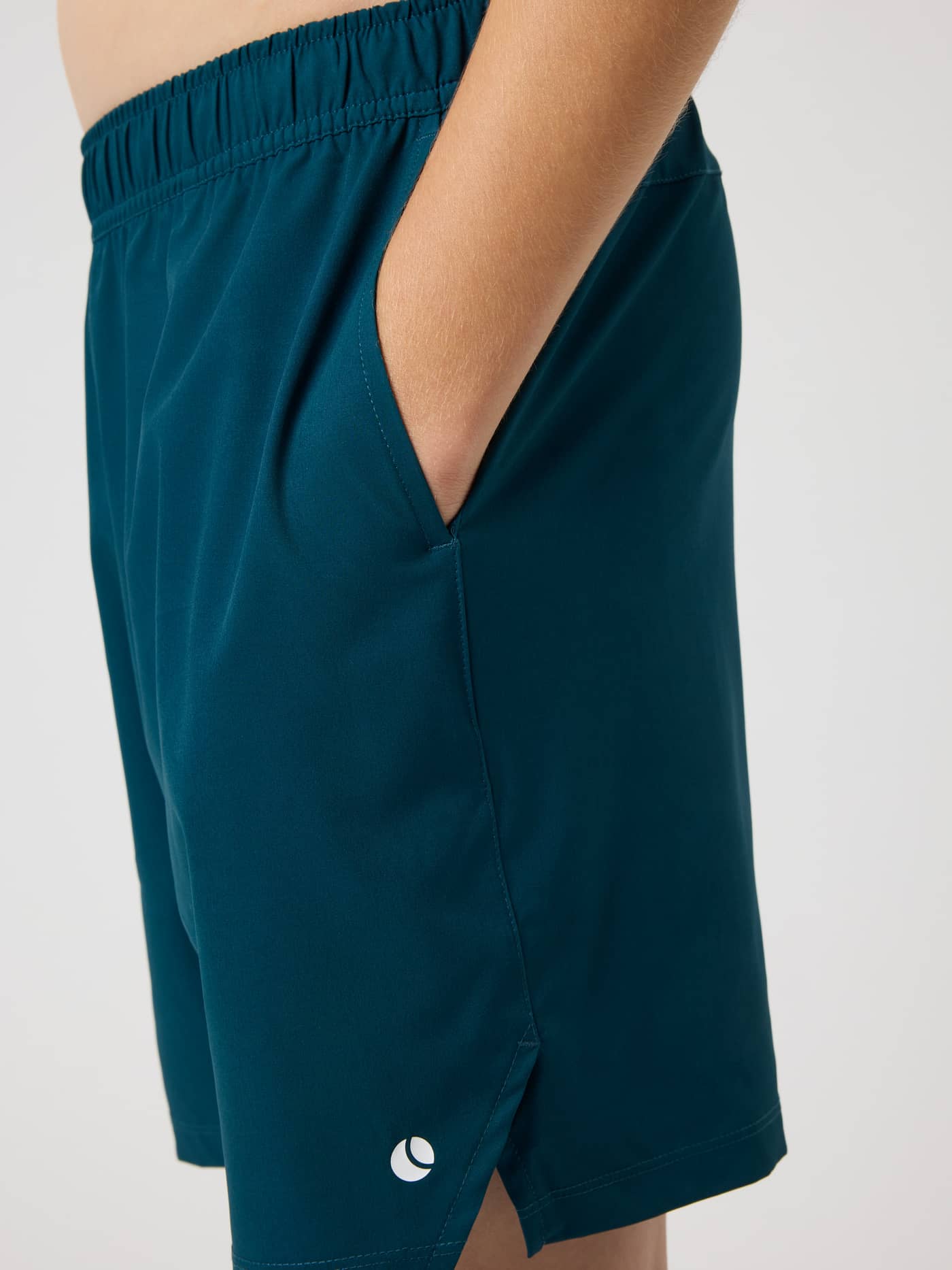Side view of kids' Ace Racquet Shorts in Reflecting Pond (Green) with a side pocket, slit, and white tennis ball logo. - Image 5