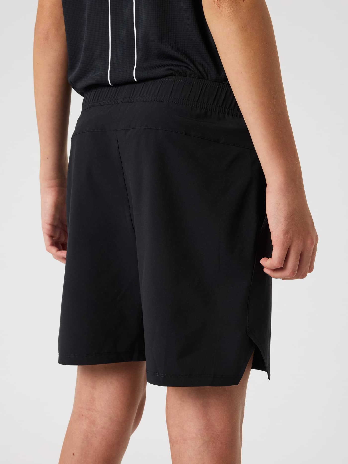 Back view of a model wearing black Björn Borg Ace Racquet Shorts for kids, featuring side slits for tennis performance. - Image 2