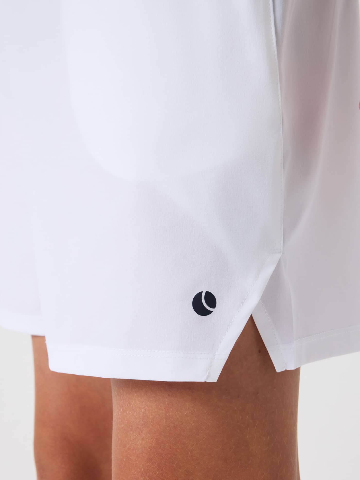 Close-up of the kids' Ace Racquet Shorts in Brilliant White (White), showing the side slit and navy tennis logo for training. - Image 4