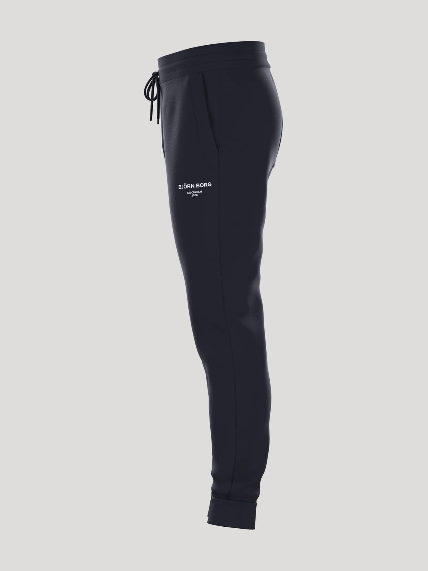 Vista lateral de los Borg Essential 1 Tapered Sweatpants en Night sky (Azul marino) con ajuste cónico y logo blanco. - Image 4