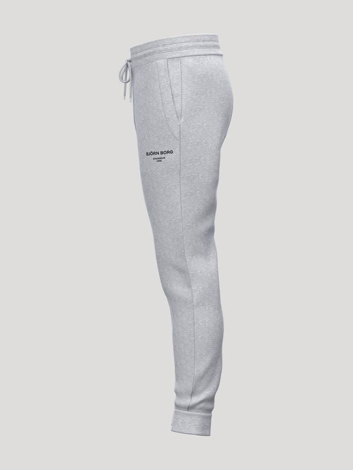 Zijaanzicht van de Borg Essential 1 Tapered Sweatpants in Light Grey Melange (Grijs) met zwart logo voor tennis. - Image 3