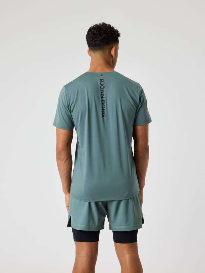 Achteraanzicht van een man in het Balsam Green (Groen) Borg Feather T-Shirt voor training en tennis met een zwart logo. - Image 2