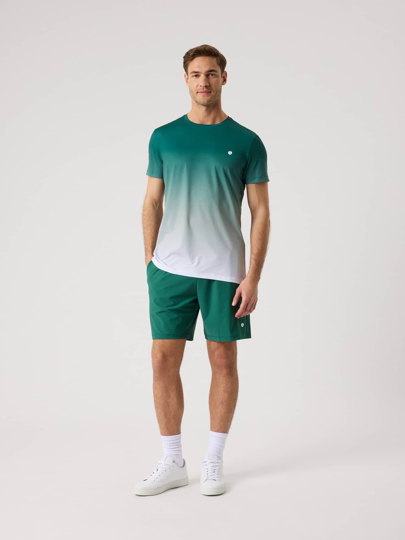 Ganzkörper-Vorderansicht eines Mannes im Ace Printed T-Shirt in Fading 2 (Grün/Weiß), ein funktionaler Tennis-Stil. - Image 4