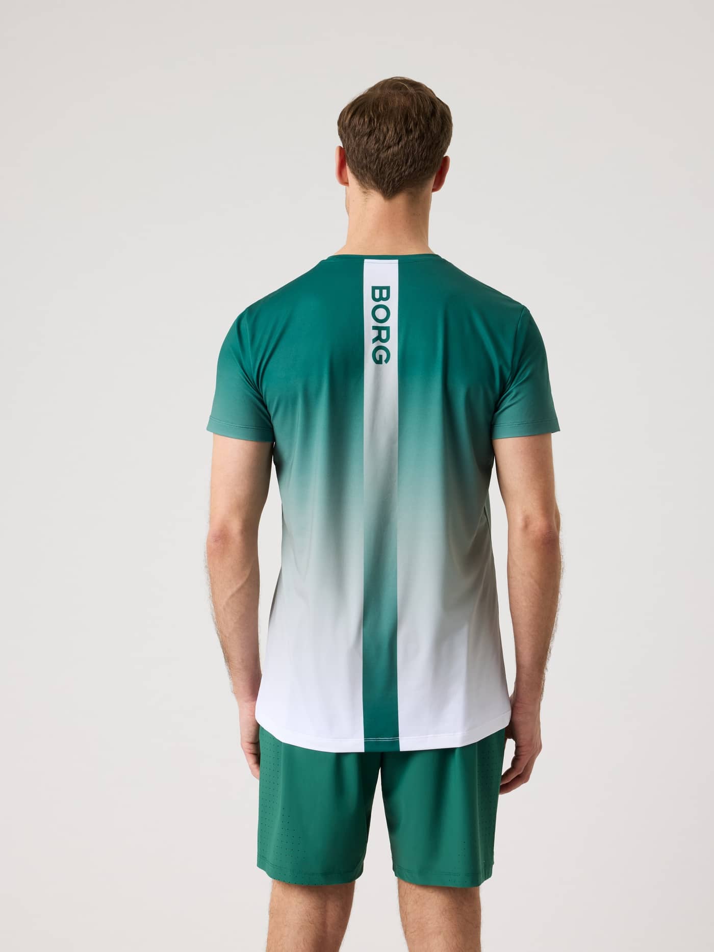 Rückansicht eines Mannes im funktionalen Björn Borg Ace Printed T-Shirt in Fading 2 (Grün/Weiß) mit grünem Tennis-Logo. - Image 3