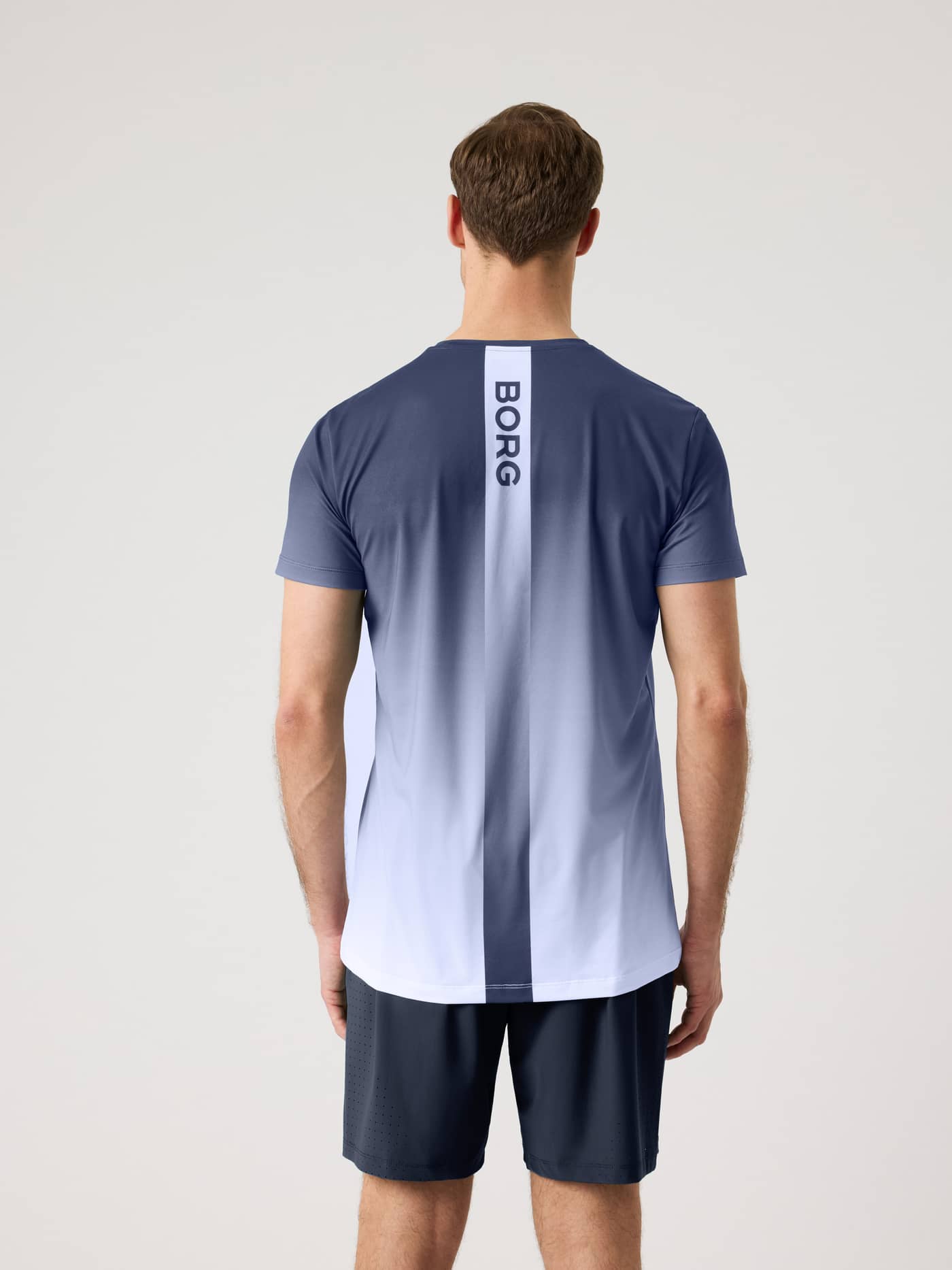 Back view of a man in the Ace Printed T-Shirt in Fading 4 (Navy/White), featuring the Borg logo for performance tennis. - Image 2