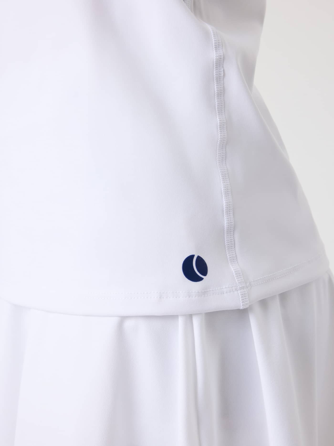 Close-up van de Ace Racerback Tank Top voor kids in Brilliant White (Wit) met een marineblauw tennislogo op de zoom. - Image 5