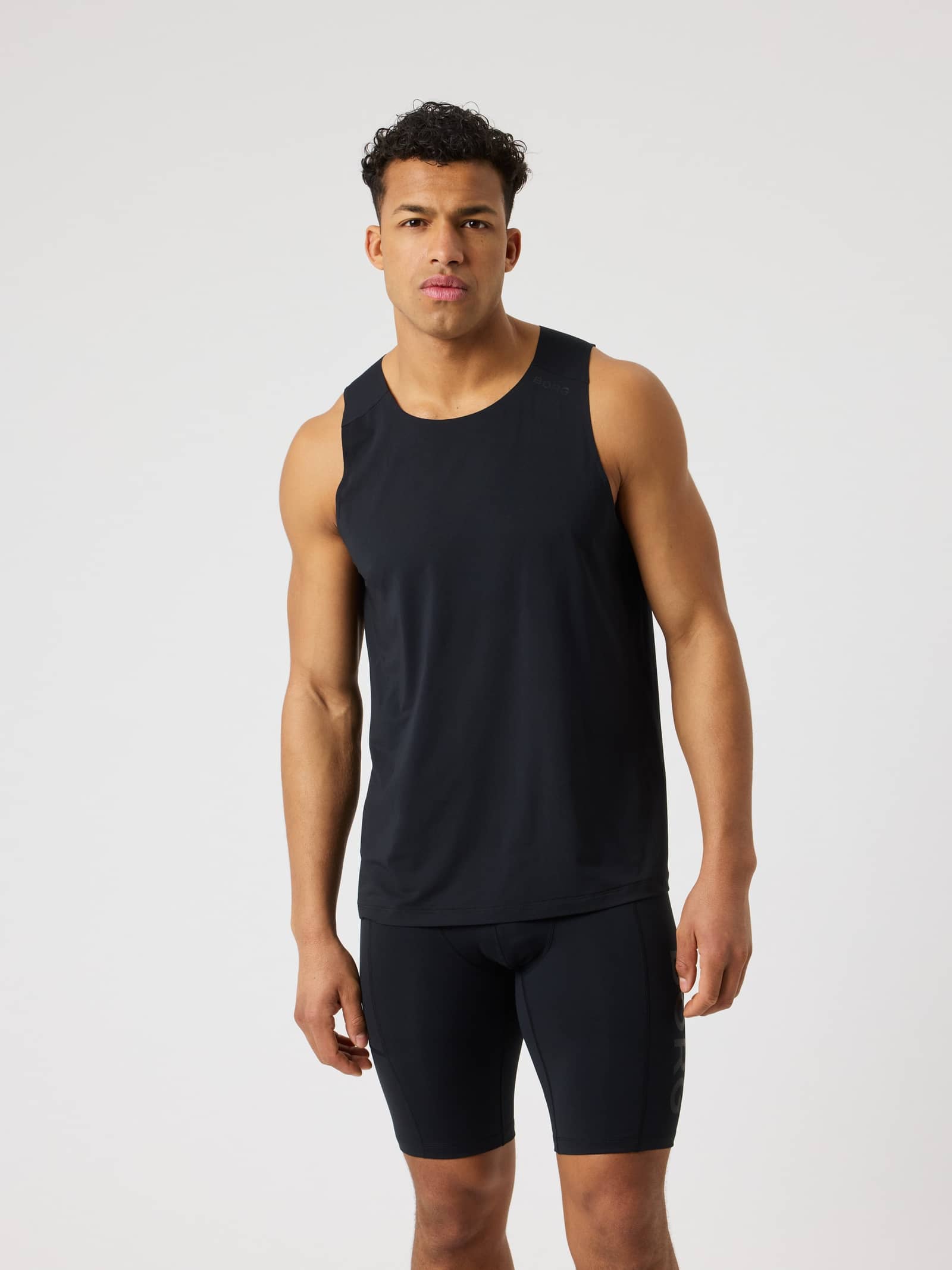 Front view of a man wearing the lightweight Borg Feather Tank in Black Beauty (Black) for performance training. - Image 1