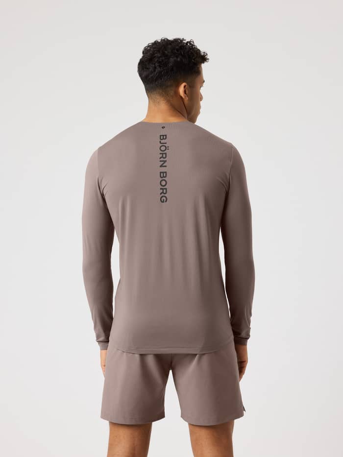 Achteraanzicht van een man in het Falcon (Bruin) Borg Feather Long Sleeve T-Shirt met zwart logo voor tennis. - Image 2