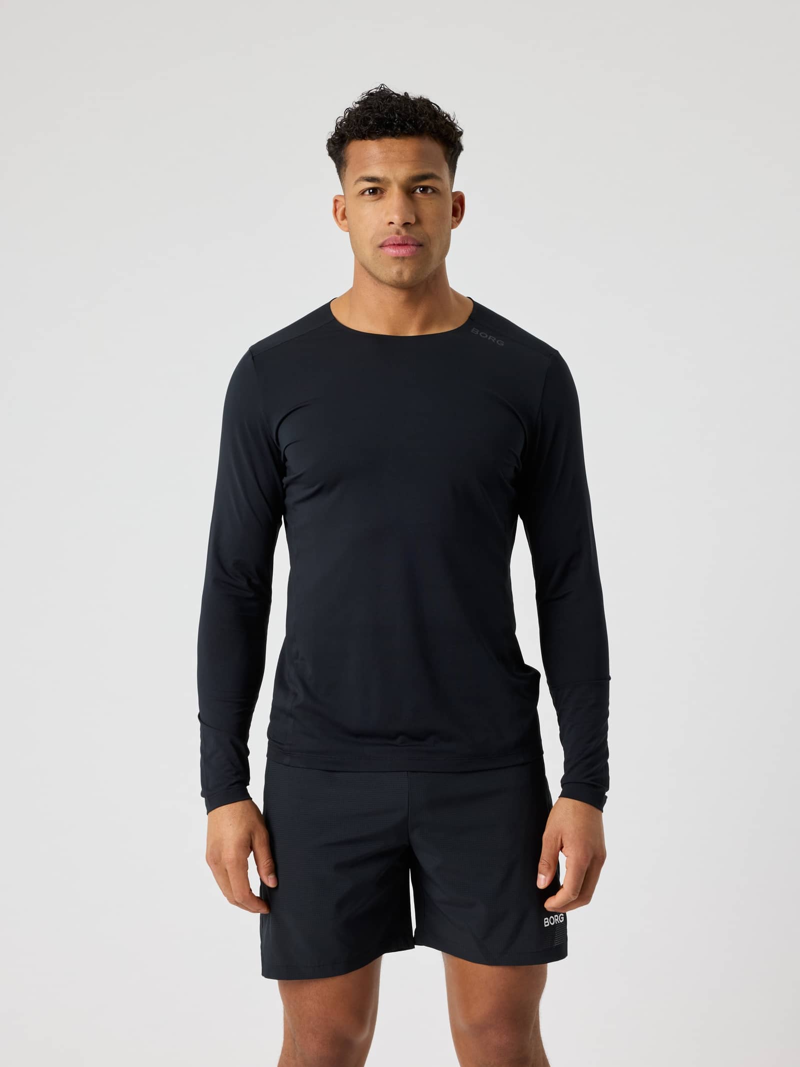 Vooraanzicht van een man in het functionele Borg Feather Long Sleeve T-Shirt in Black Beauty (Zwart) voor tennis en gym. - Image 1