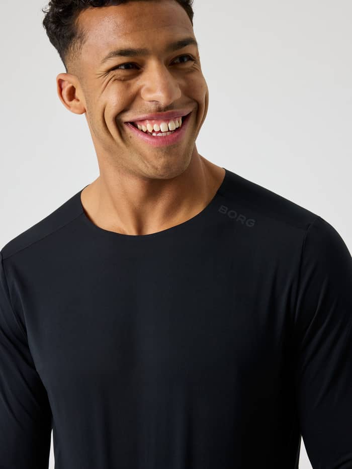 Close-up van een man in het Borg Feather Long Sleeve T-Shirt in Black Beauty (Zwart) met zwart logo voor training. - Image 5