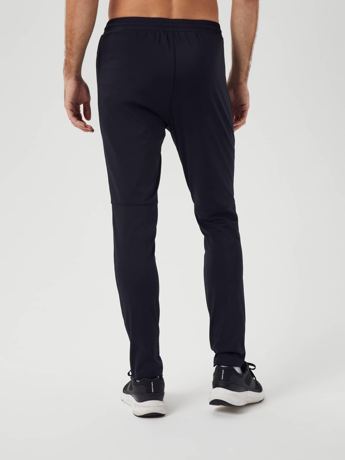 Rückansicht eines Mannes in Ace Training Pants in Black Beauty (Schwarz) für funktionalen Style beim Tennis und Training. - Image 2