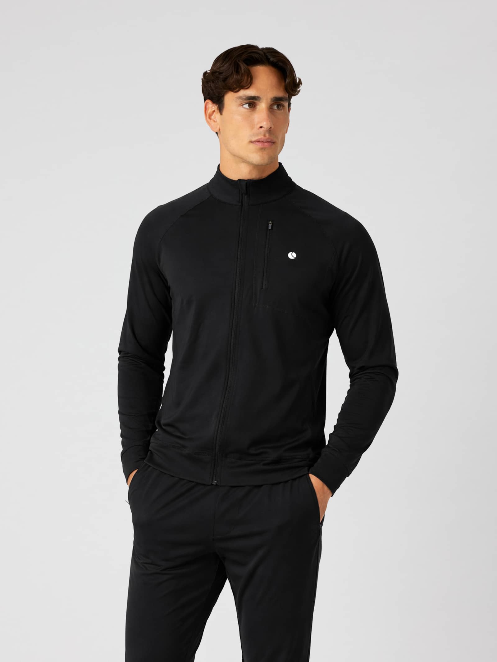 Front view of a man in the Björn Borg Ace Training Jacket in Black Beauty (Black) with a white logo for training and tennis. - Image 1