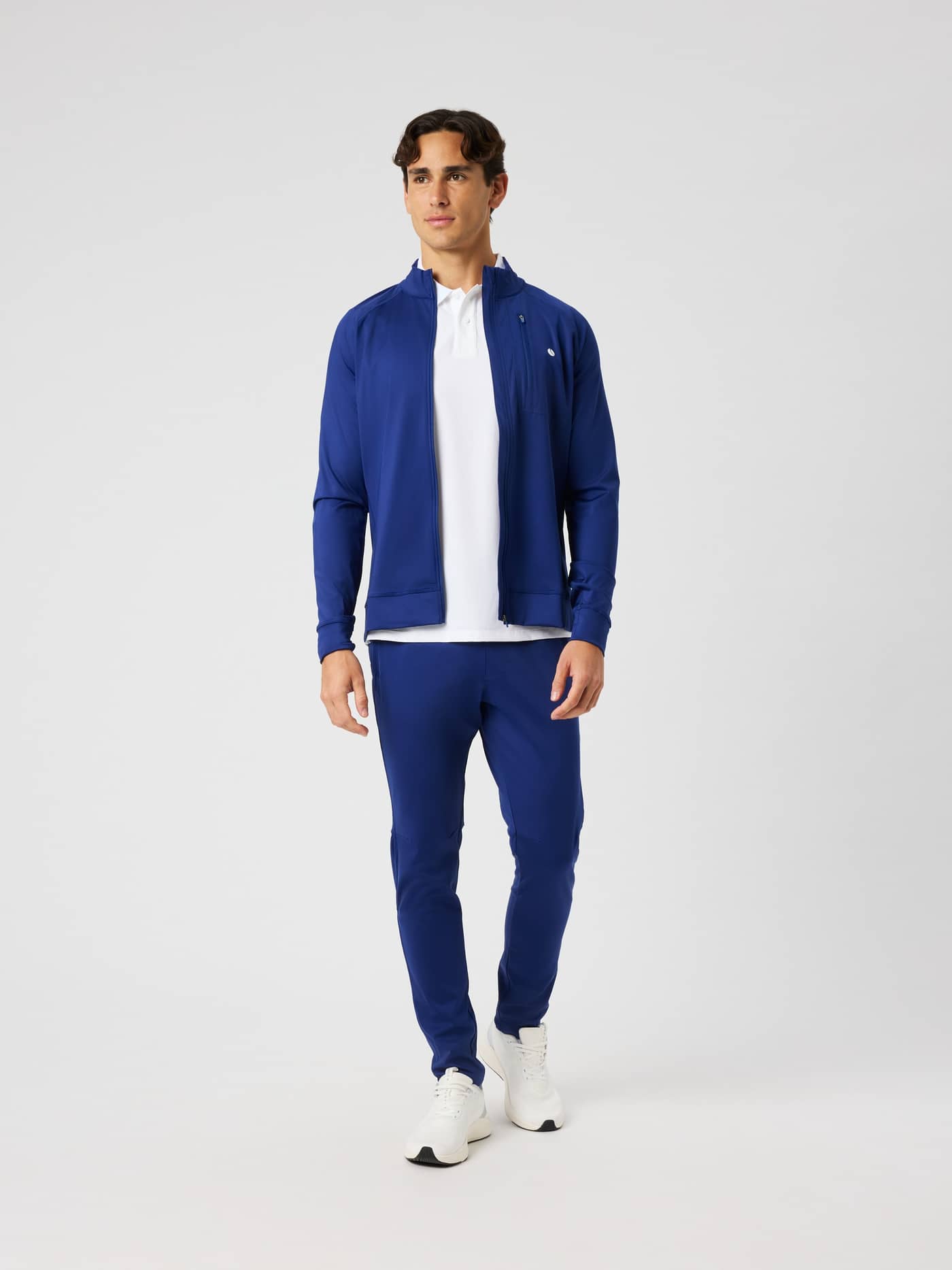Full-body front view of a man wearing the Blue Depths (Blue) Ace Training Jacket, combining tennis style and function. - Image 3