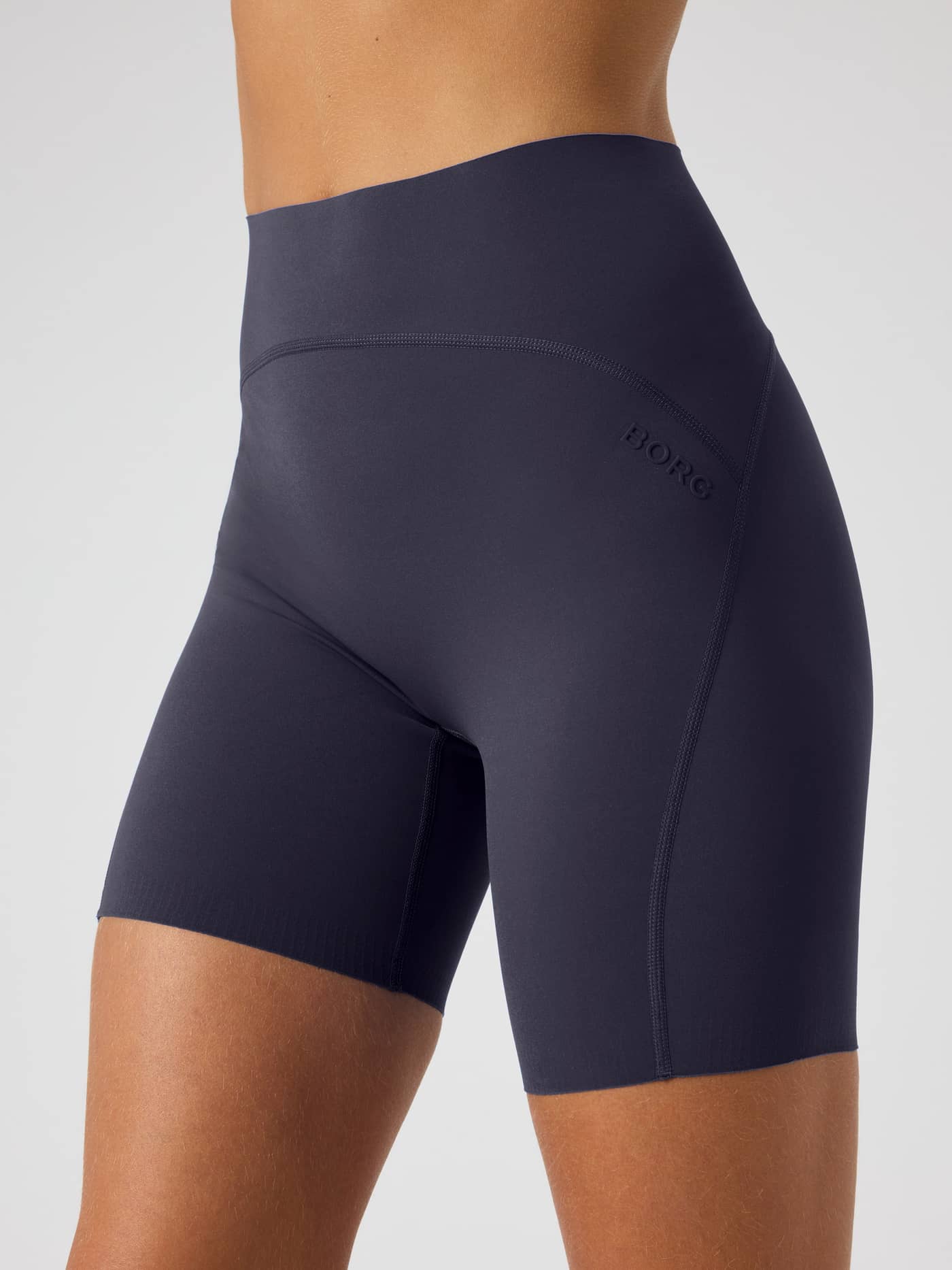 Side view of the Borg Sleek Shorts in Odyssey Gray (Navy) for women’s training, showing the tonal logo and fit. - Image 4