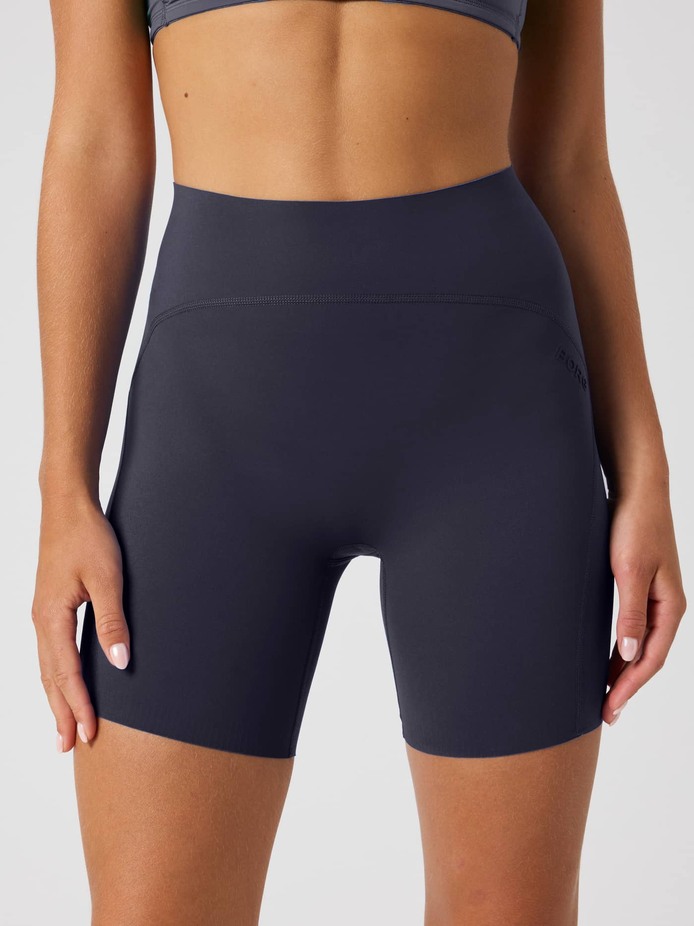 Front view of a model wearing the high-waisted Borg Sleek Shorts in Odyssey Gray (Navy) for women's training. - Image 1