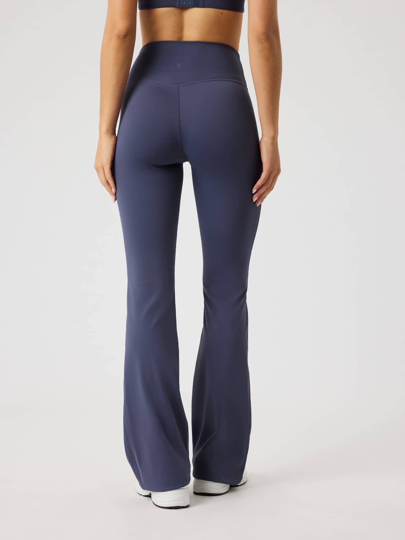 Back view of a model in training-ready, high-waisted Borg Flare Tights Regular in Odyssey Gray (Navy) with a tonal logo. - Image 2