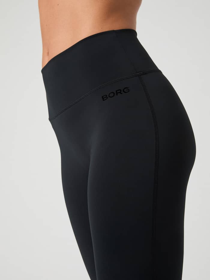 Seitliche Nahaufnahme der Borg Flare Tights Petite in Black Beauty (Schwarz) mit schwarzem Logo, ideal für das Training. - Image 3