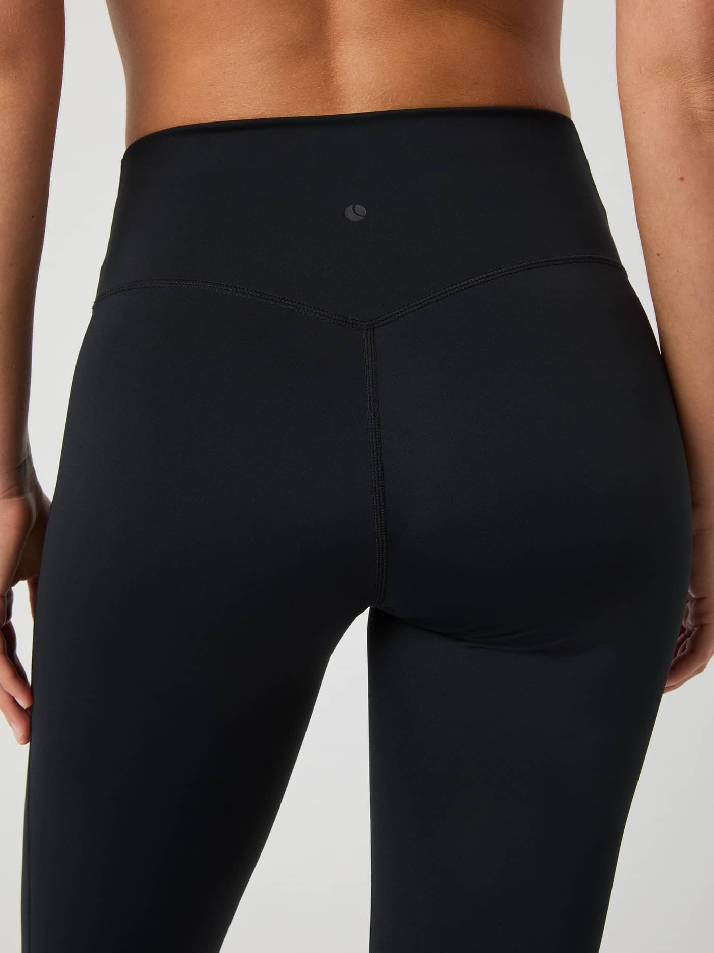 Back view close-up of the high-waisted Borg Flare Tights Petite in Black Beauty (Black) with a tonal logo for training. - Image 4