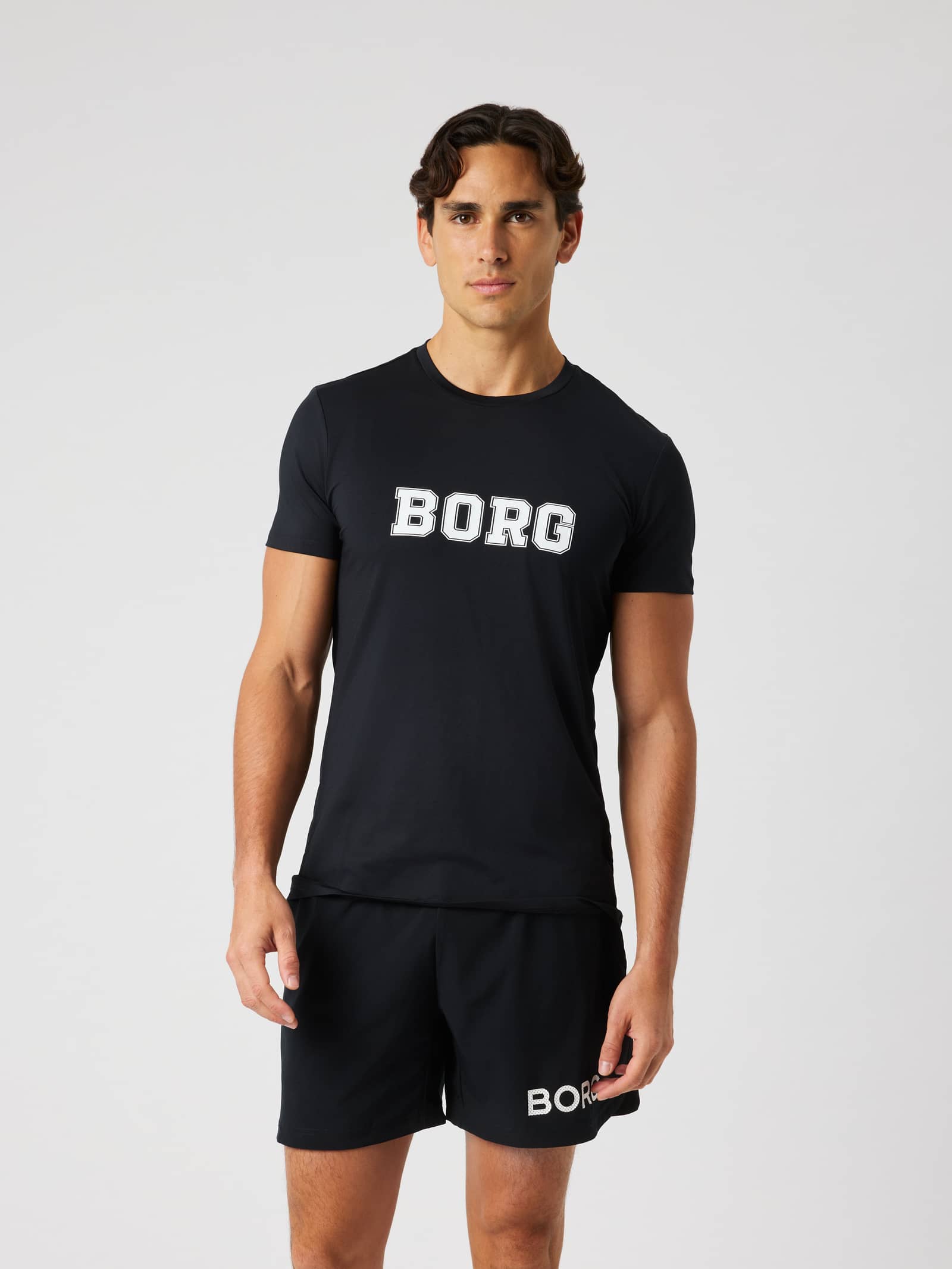Vue de face d'un homme en Borg Graphic T-Shirt Black Beauty (Noir), t-shirt de tennis et d'entraînement à logo blanc. - Image 1