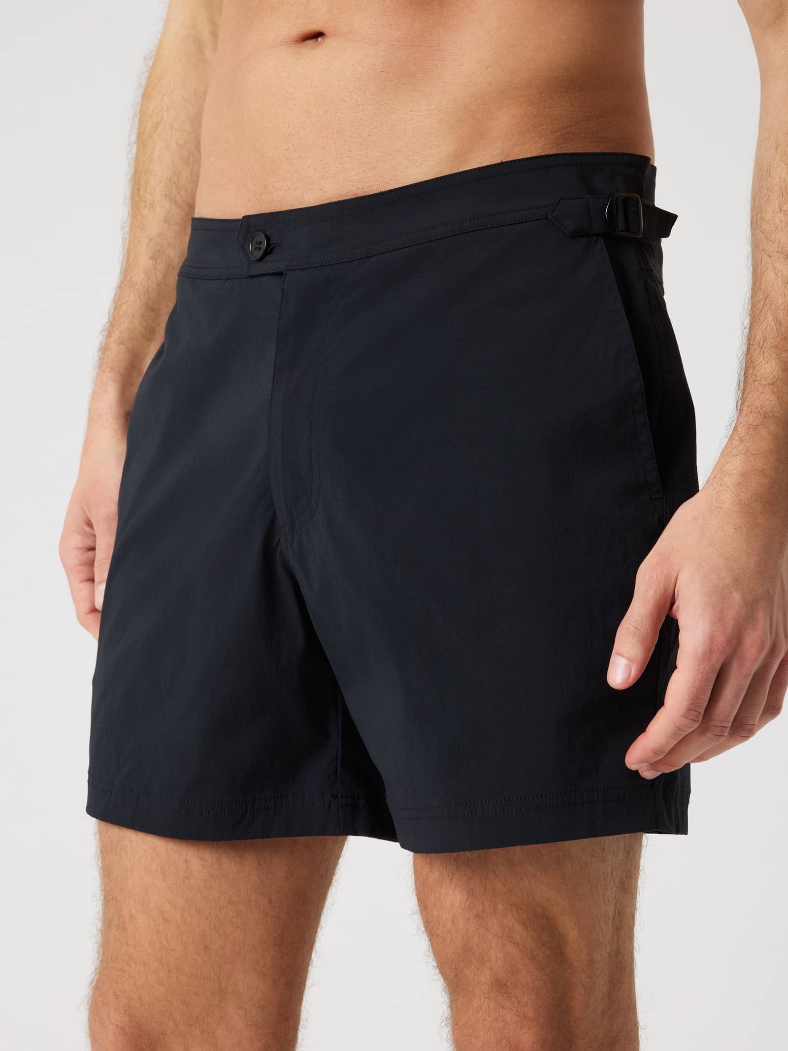 Close-up of a man wearing the Borg Tailored Swim Shorts in Black Beauty (Black) with adjustable side buckles. - Image 1