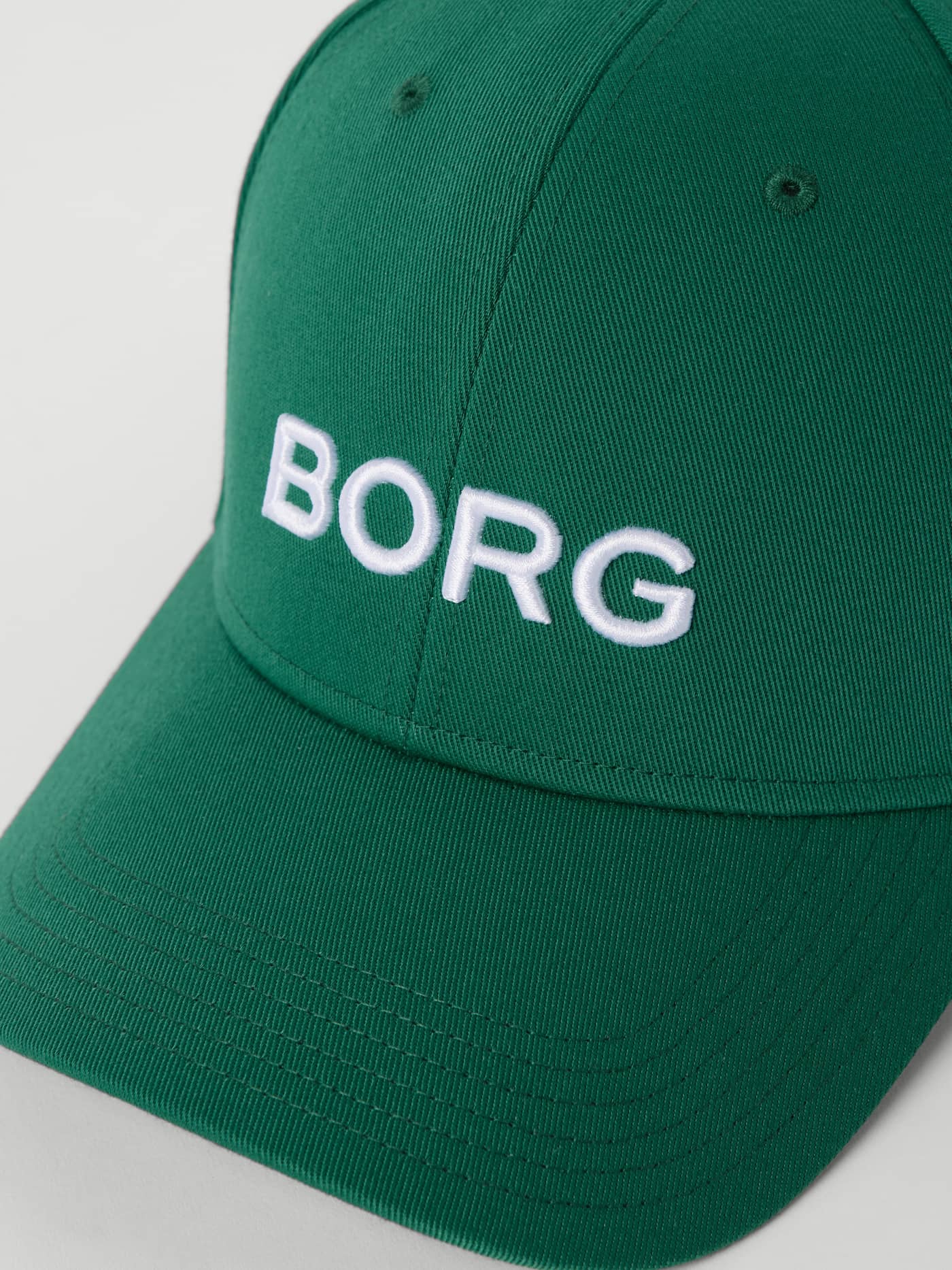 Close-up of the Borg Baseball Cap in Posy Green (Green) featuring a white embroidered logo for a classic tennis style. - Image 3