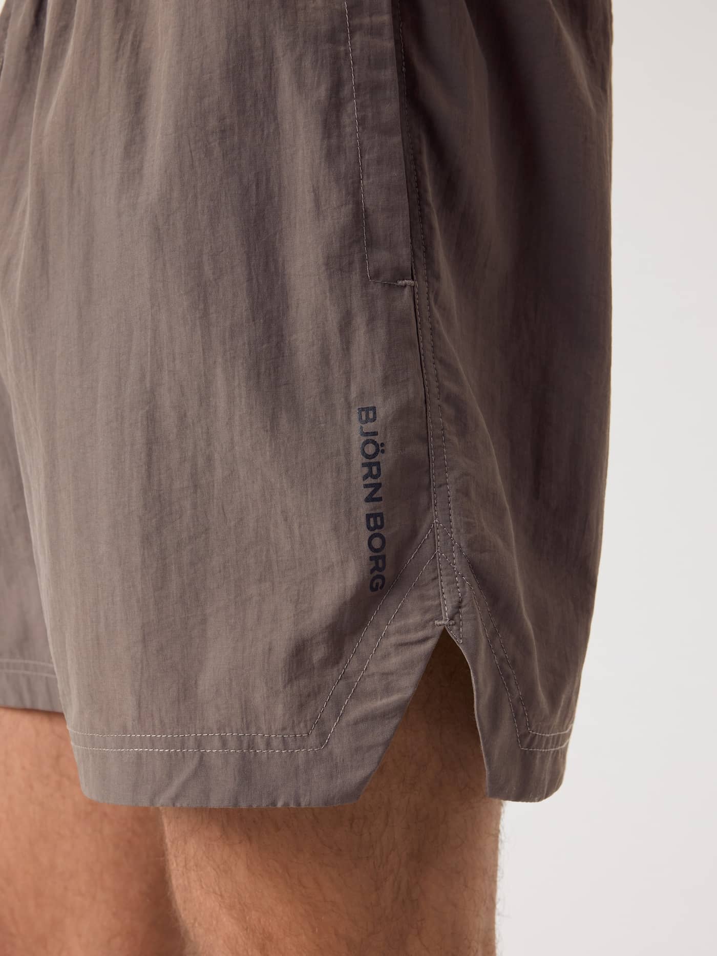 Side close-up of the training Borg Gym Shorts 5 Inch in Falcon (Brown) with a black logo and side slits for mobility. - Image 4