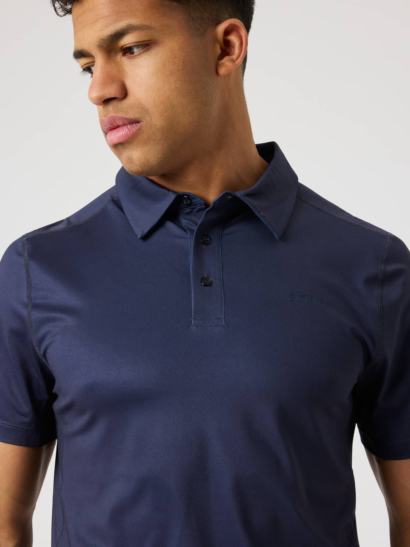 Borg Sports Polo Shirt i Night sky (Mørkeblå) i nærbillede med navy logo, ideel til stil og performance til tennis. - Image 4