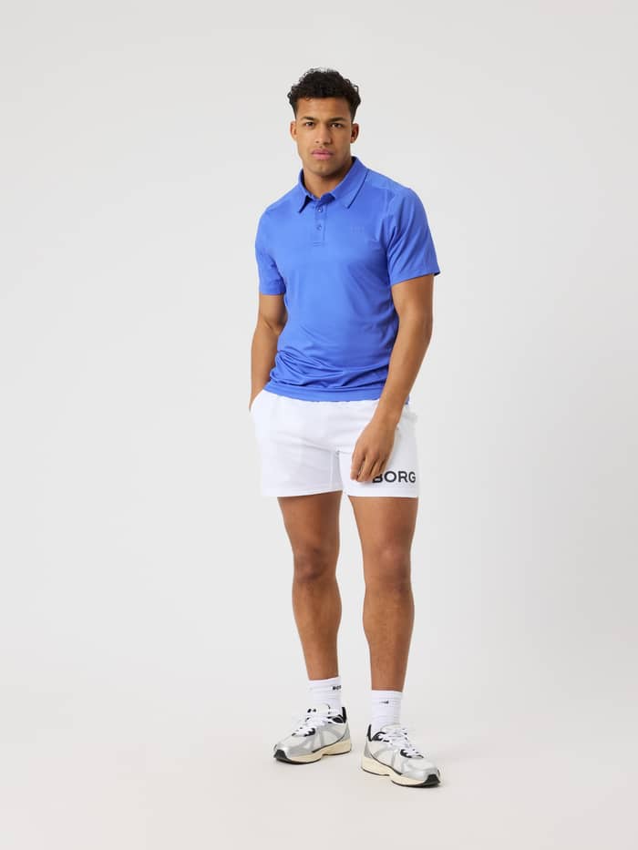 Full-body front view of a man wearing the Amparo Blue (Blue) Borg Sports Polo Shirt, ideal for tennis and training. - Image 3