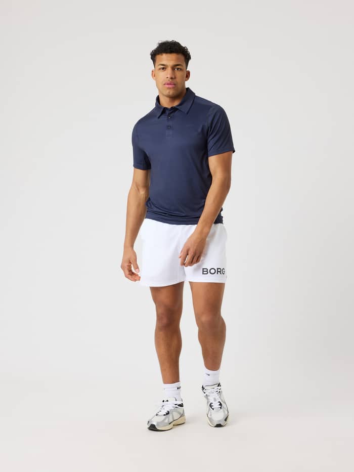 Full-body front view of a man wearing the Borg Sports Polo Shirt in Night sky (Navy), styled for tennis performance. - Image 3
