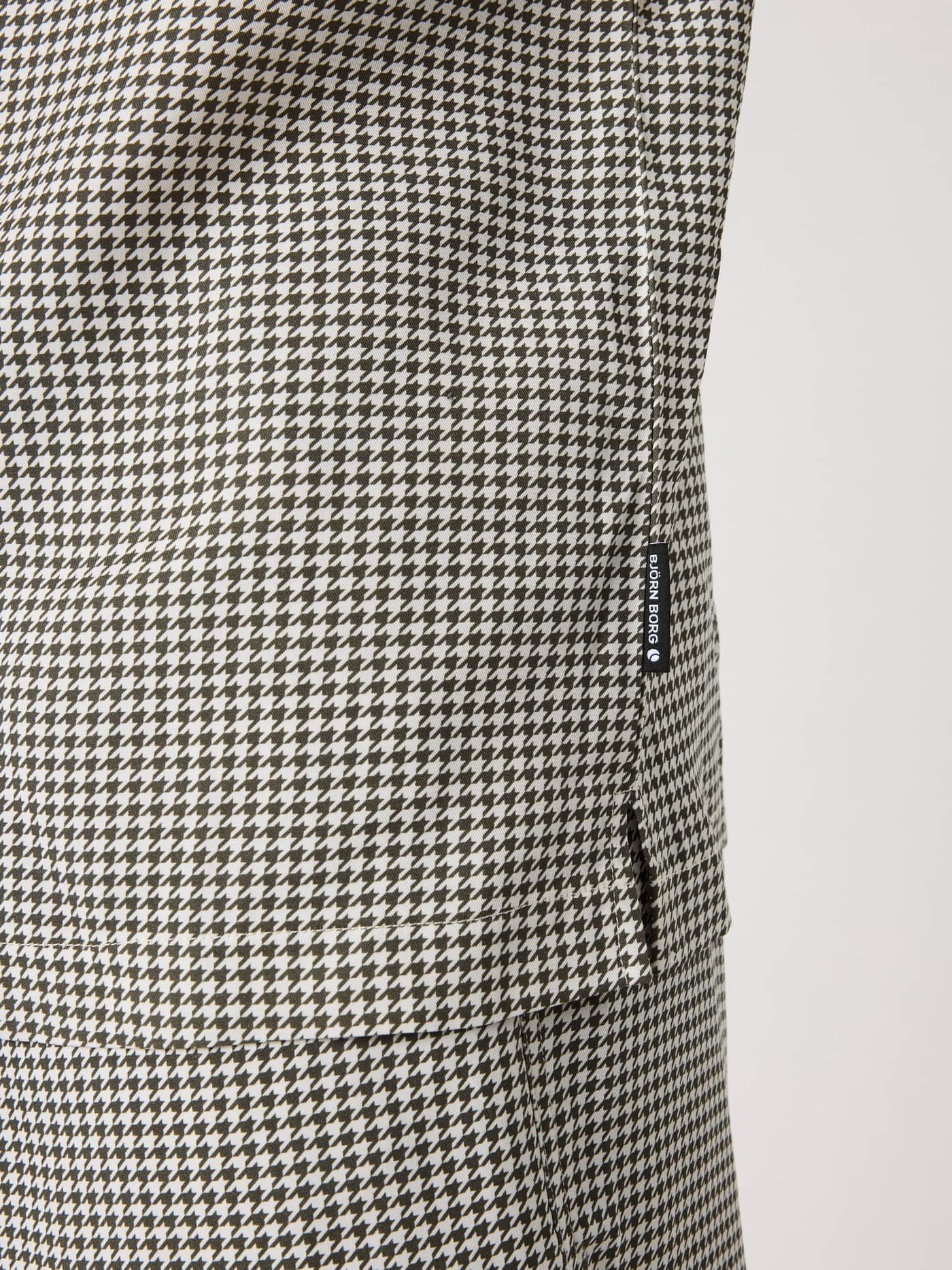 Close-up of the Borg Lyocell Resort Shirt in Houndstooth 3 (Black, White) showing the side slit and black flag label. - Image 7