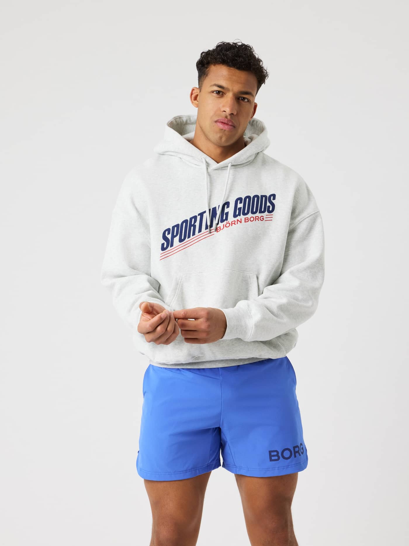 Front view of a man in the Borg Oversized Hoodie in Ultra Light Grey Melange (Grey) with a navy and red tennis graphic. - Image 10