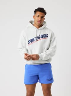 Front view of a man in the Borg Oversized Hoodie in Ultra Light Grey Melange (Grey) with a navy and red tennis graphic. - Image 10