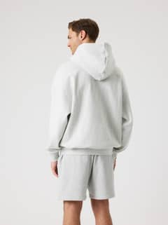Back view of a man wearing the Borg Oversized Hoodie in Ultra Light Grey Melange (Grey) with a double layer hood. - Image 7