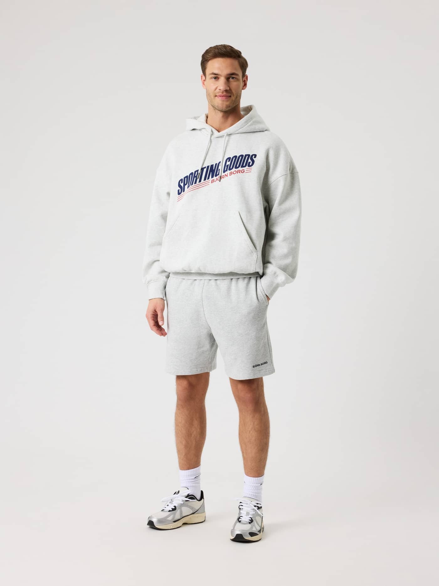 Front view of a man in the Borg Oversized Hoodie in Ultra Light Grey Melange (Grey) with a navy logo for style and function. - Image 5