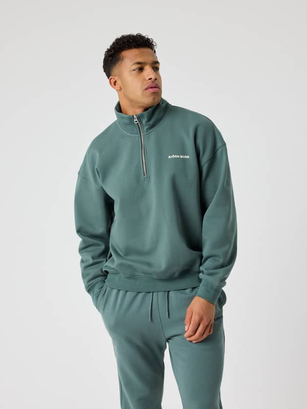 Vue de face du Borg Oversized Half-Zip en Balsam Green (Vert) avec logo blanc, alliant style et fonctionnalité.