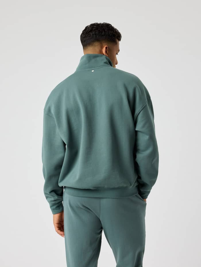 Achteraanzicht van een man in de Björn Borg Oversized Half-Zip in Balsam Green (Groen) met relaxte pasvorm en tennisprint. - Image 2