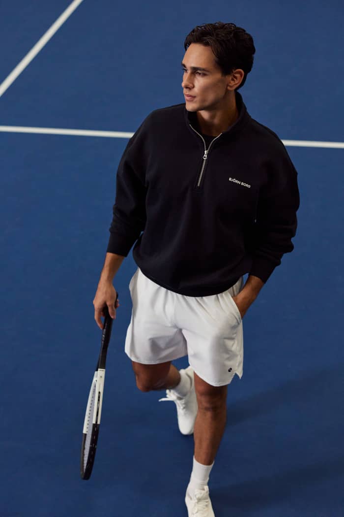 Front view of a man wearing the Borg Oversized Half-Zip in Black Beauty (Black) holding a tennis racket on a court.