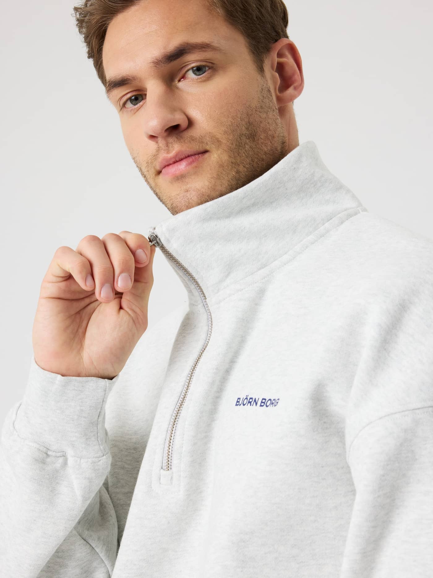 Nahaufnahme des Borg Oversized Half-Zip in Ultra Light Grey Melange (Grau) mit blauem Logo für Performance beim Training. - Image 6