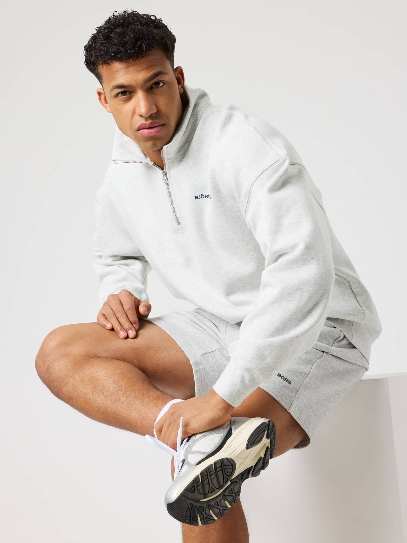 Mann im Borg Oversized Half-Zip in Ultra Light Grey Melange (Grau) mit navyfarbenem Logo und funktionalem, stilvollem Fit. - Image 2